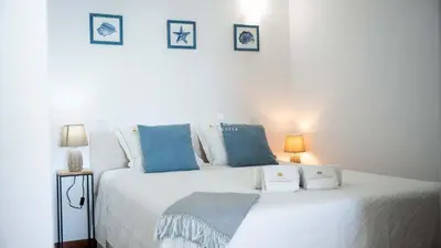 a bedroom with a large white bed with blue pillows at Brisa Mar-Aveiros Apatment by Dalma Portuguesa in Albufeira