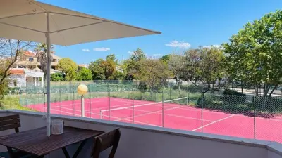 a tennis court with a table and an umbrella at Aqua Plaza 2 Bedr swimming pool 5 min to the beach in Olhos de Água