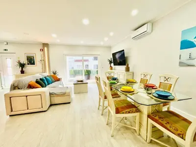 a living room with a table and chairs and a couch at BrisaMarVilas Sea view, 5 min Walk to Town & Beach in Albufeira