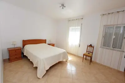 a bedroom with a bed and a chair and a window at Appartement Quarteira in Quarteira