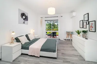 a white bedroom with a bed and a desk at Vilamoura Family Escape in Quarteira