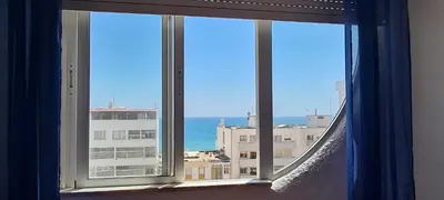 a window with a view of the ocean and buildings at Quarteira Azul in Quarteira