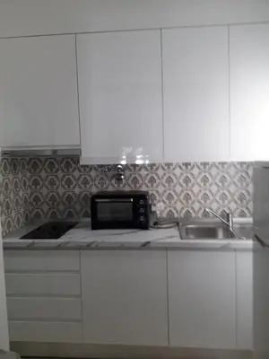 a kitchen with white cabinets and a sink at Quarteira Azul in Quarteira