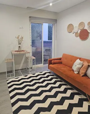 a living room with a orange couch and a black and white rug at Oldtown Nightlife in Faro