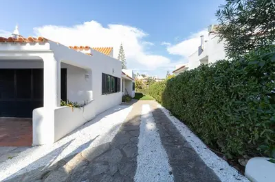 a pathway leading to a white house with a hedge at Villa Uno by HelloVacations in Loulé