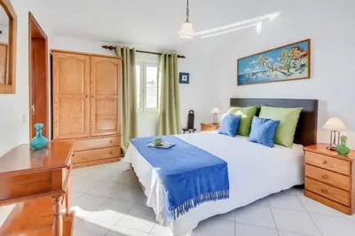 a bedroom with a large bed with blue and green pillows at Casa Sol in Albufeira
