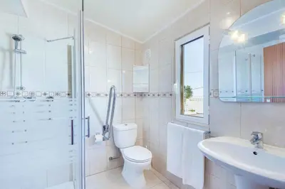a white bathroom with a toilet and a sink at Casa Sol in Albufeira