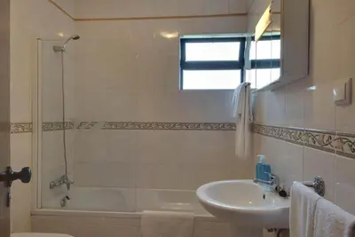 a white bathroom with a sink and a bath tub at Villa Praia in Albufeira