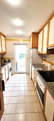 a kitchen with a tile floor and a door to a yard at T2 Vilamoura - com piscina e campo tenis in Vilamoura