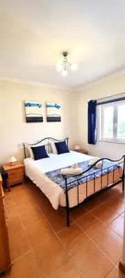 a bedroom with a large bed with blue pillows at T2 Vilamoura - com piscina e campo tenis in Vilamoura