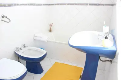a bathroom with a blue sink and a toilet at Rich & Poor Hostel Albufeira in Albufeira
