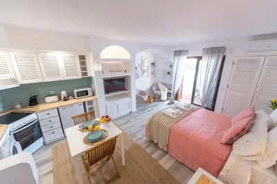 a bedroom with a bed and a kitchen with a table at Albufeira Central Studio w swim pool and Seaview in Albufeira