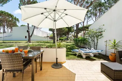 a table with an umbrella on a patio at Vilamouratenis Sunscape by SAPvillas in Vilamoura