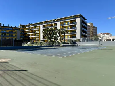 a tennis court in front of a large building at Quarteira Stylish 3 with Pool by Homing in Quarteira