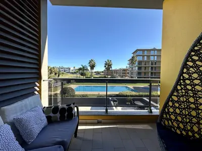 a balcony with a couch and a view of a pool at Quarteira Stylish 3 with Pool by Homing in Quarteira