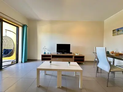 a living room with a table and a tv at Quarteira Stylish 3 with Pool by Homing in Quarteira