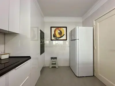 a white kitchen with a refrigerator and a stool at Vilamoura Grand Terrace with Pool by Homing in Vilamoura