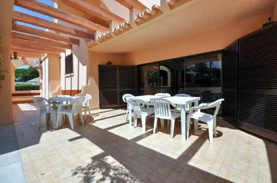 a patio with white tables and chairs on a building at Villa Gardenia in Quarteira