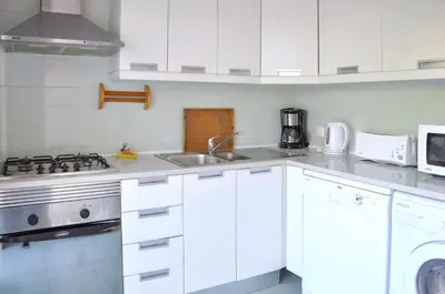 a white kitchen with a sink and a stove at Vista Golfe in Quarteira