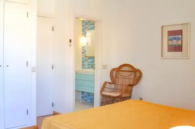 a bedroom with a bed and a wicker chair at Vista Golfe in Quarteira