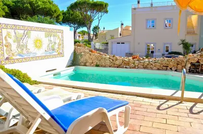 a villa with a swimming pool and two lawn chairs at Vista Golfe in Quarteira