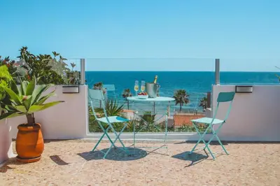 two chairs and a table on a balcony with the ocean at Casa do Cacto in Olhos de Água