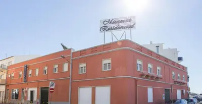 a red building with a sign on top of it at Residencial Miramar in Quarteira