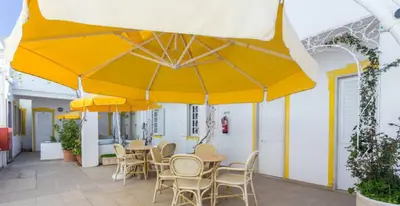 a patio with tables and chairs under yellow umbrellas at Residencial Miramar in Quarteira