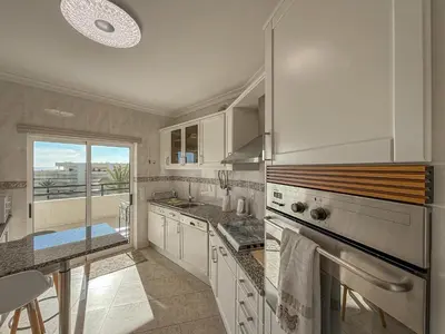a kitchen with white cabinets and a large window at Luxury Apart wStunning Sea Views, walk Galé Beach Albufeira in Albufeira