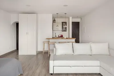a white living room with a white couch and a kitchen at Estúdio 21 em Santa Bárbara de Nexe - Faro in Santa Bárbara de Nexe