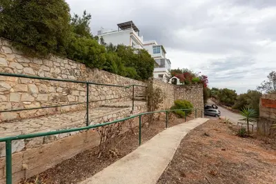 a stone wall with a fence next to a car at Estúdio 21 em Santa Bárbara de Nexe - Faro in Santa Bárbara de Nexe