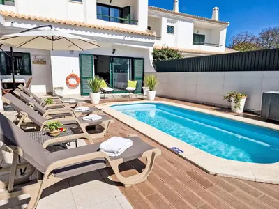 a swimming pool in a yard with chairs and a house at Holiday Home V2 Caliços - VIP Properties by Interhome in Albufeira