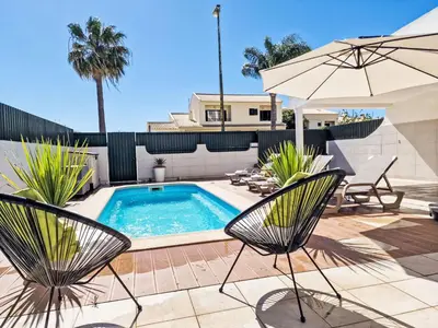 a swimming pool with two chairs and an umbrella at Holiday Home V2 Caliços - VIP Properties by Interhome in Albufeira