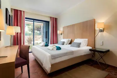 a hotel room with a large bed and a desk and a window at 2 bedroom Vila Sol Golf Resort in Quarteira