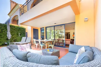 a patio with blue couches and a table and chairs at 2 bedroom Vila Sol Golf Resort in Quarteira