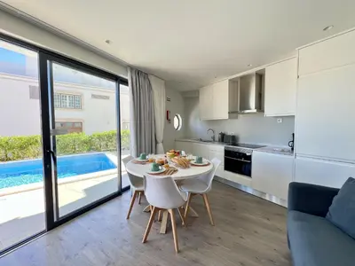 a kitchen and living room with a table and chairs at Albufeira Stylish 2 With Pool by Homing in Albufeira