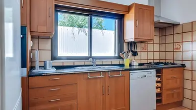 a kitchen with wooden cabinets and a sink and a window at Villa Frederique by Gabi Miguel in Albufeira