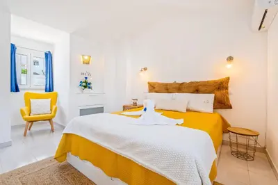 a bedroom with a large bed and a yellow chair at Stay in Old Town - 5 min walking to the beach in Albufeira