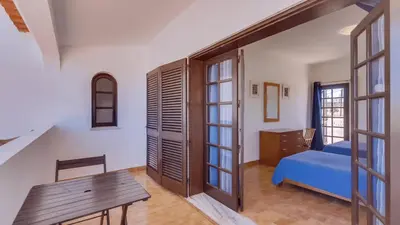 a bedroom with a blue bed and a wooden table at Villa Frederique in Albufeira