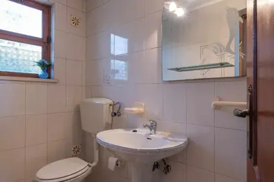 a white bathroom with a toilet and a sink at Villa Andrea in Albufeira