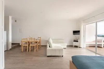 a white living room with a table and a chair at Estúdio 24 em Santa Bárbara de Nexe - Faro in Colmeal