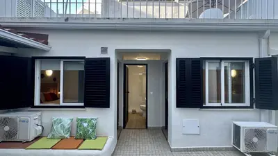 a white house with black shuttered windows and a patio at Vilanova by Check-in Portugal in Albufeira