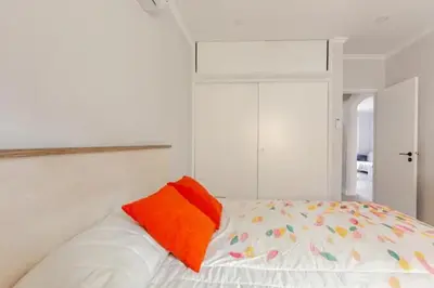 a white bed with an orange pillow on it at BrisaMarVilas Sea view, 5 min Walk to Town & Beach 12e13 in Albufeira