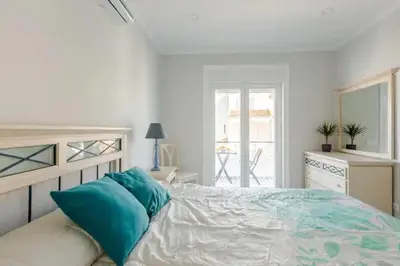 a white bedroom with a bed with blue pillows at BrisaMarVilas Sea view, 5 min Walk to Town & Beach 12e13 in Albufeira