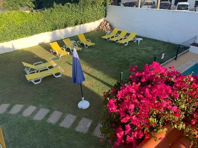 a patio with lounge chairs and an umbrella and flowers at Luxury Villa private pool, Albufeira in Albufeira
