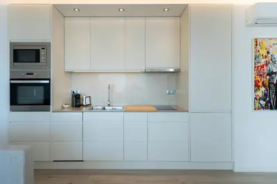 a kitchen with white cabinets and a sink at Marina Mar Bela Vista by SAPvillas in Vilamoura