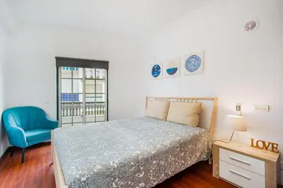 a bedroom with a bed and a blue chair at Vivenda das Conchas - Just 50 Meters from the Beach in Quarteira