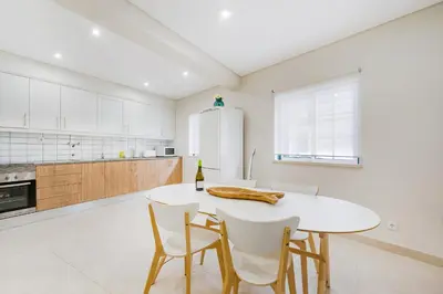 a white kitchen with a white table and chairs at Vivenda das Conchas - Just 50 Meters from the Beach in Quarteira