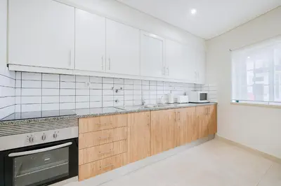a kitchen with white appliances and wooden cabinets at Vivenda das Conchas - Just 50 Meters from the Beach in Quarteira