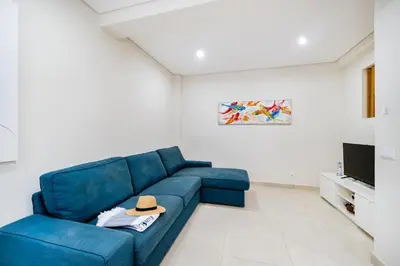 a living room with a blue couch and a tv at Vivenda das Conchas - Just 50 Meters from the Beach in Quarteira
